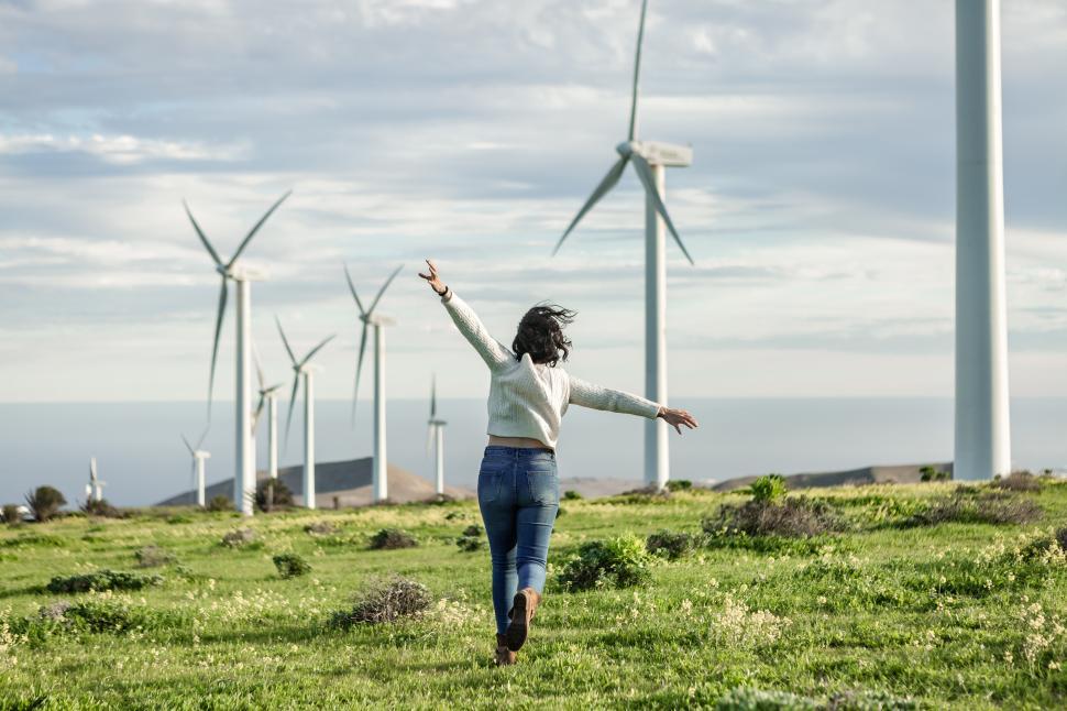 Free Image of Unrecognizable woman running in meadow with windmills 
