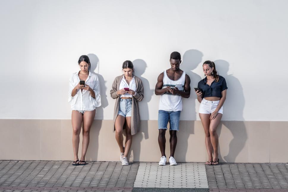 Free Image of Group of diverse people using smartphones on city street 