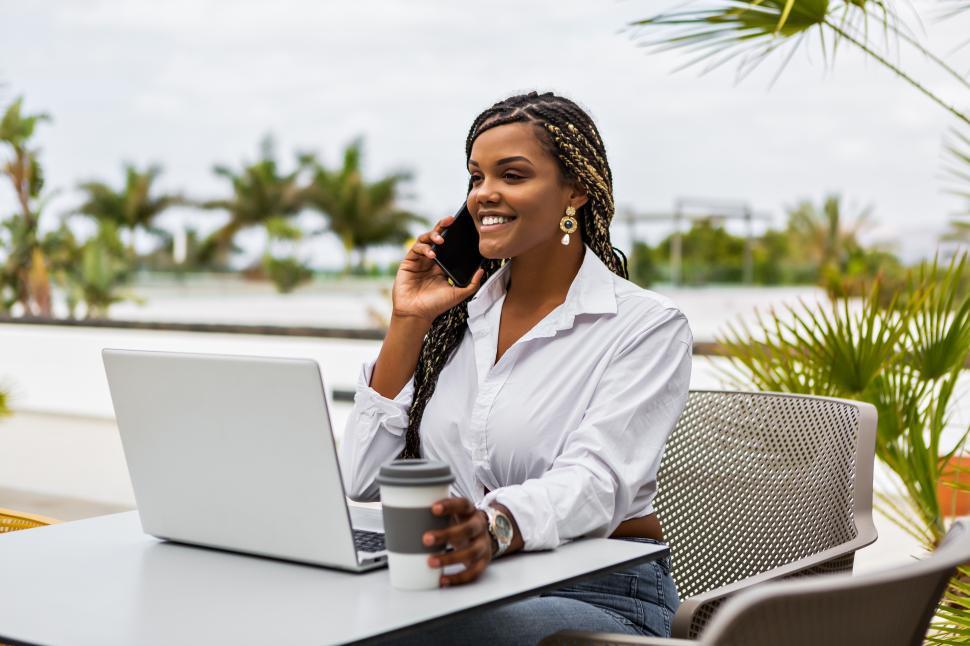 Free Image of Cheerful woman with her laptop talking with cel 