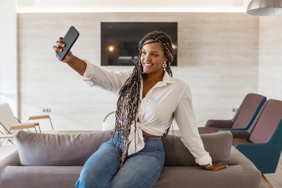 Free Image of Cheerful woman in her home using phone to take a selfie 