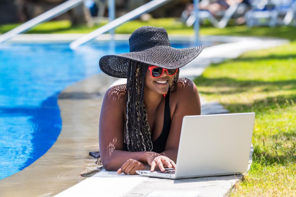 Free Image of Woman lying on the edge of the pool with a laptop 