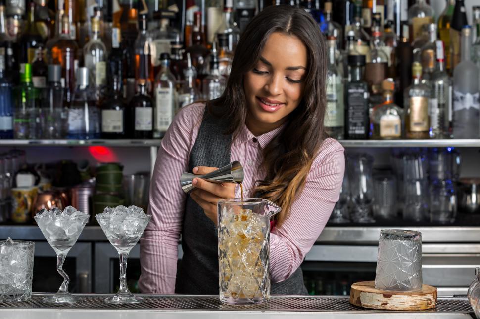 Free Image of Positive female barkeeper making cocktail in bar 