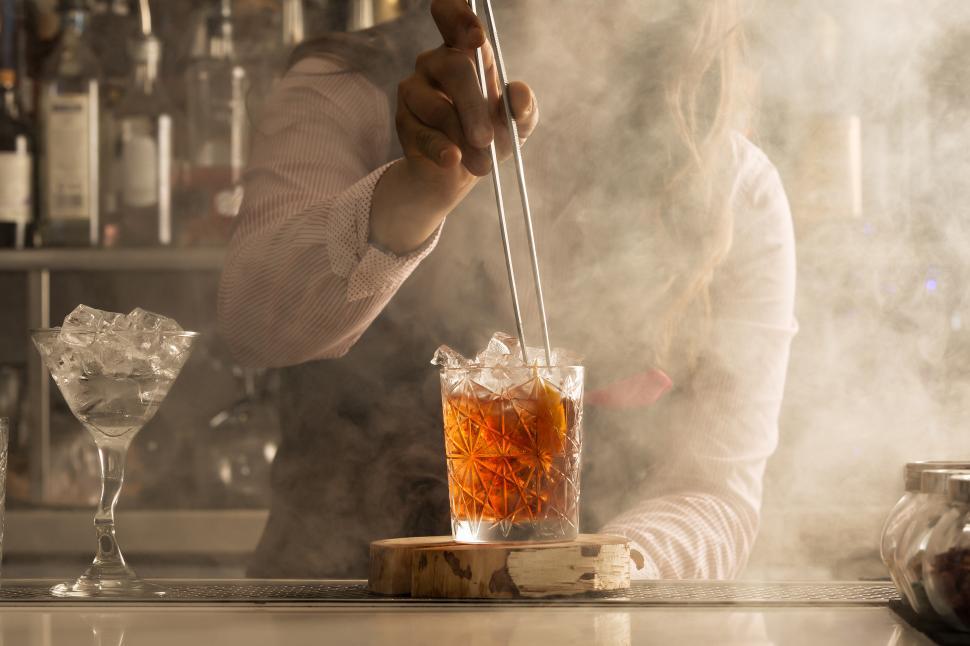 Free Image of Bartender with tongs adding ingredient into cocktail 