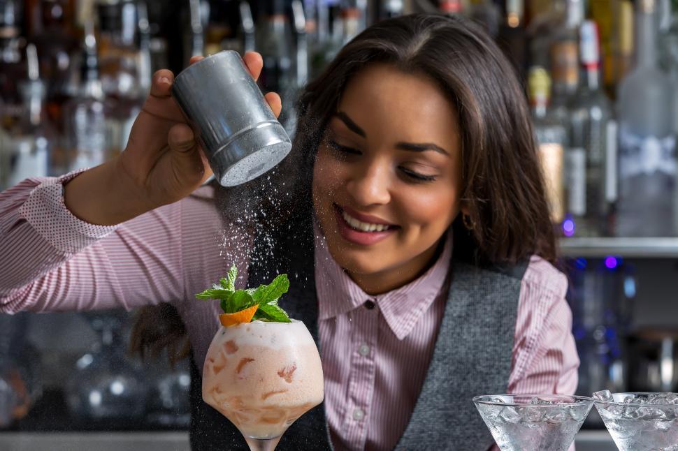 Free Image of Happy female barkeeper adding powdered sugar to cocktail 