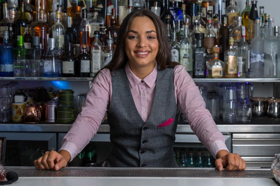 Free Image of Cheerful female bartender standing behind counter in bar 