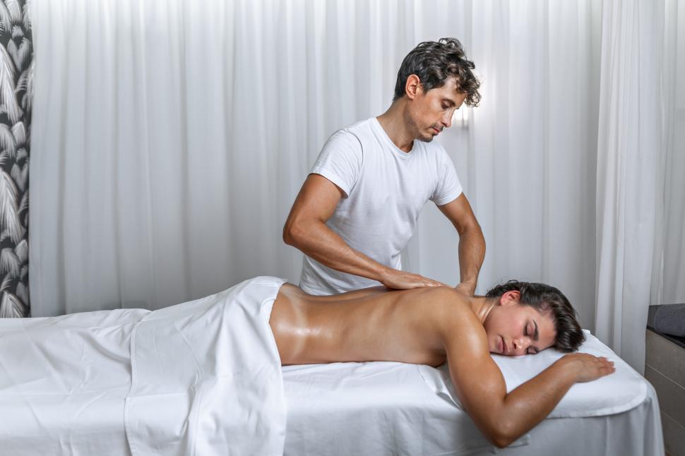 Free Image of Male masseur performing a back massage on woman at spa 