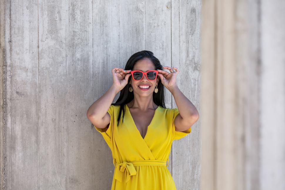 Free Image of View near a column of a young Latina woman in yellow dress 