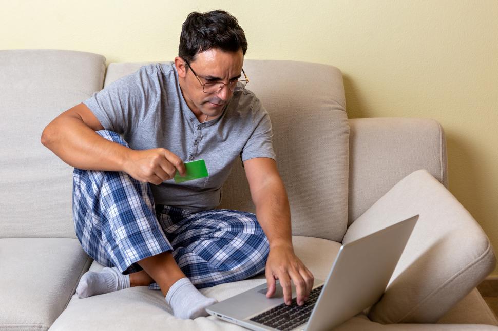 Free Image of Young Caucasian male sitting on a couch using a laptop computer 