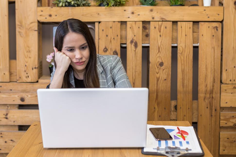 Free Image of Bored woman leaning on hand while using laptop 
