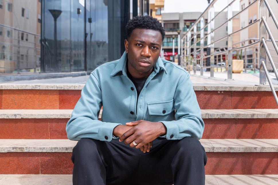Free Image of Confident ethnic guy sitting on stairs on street 