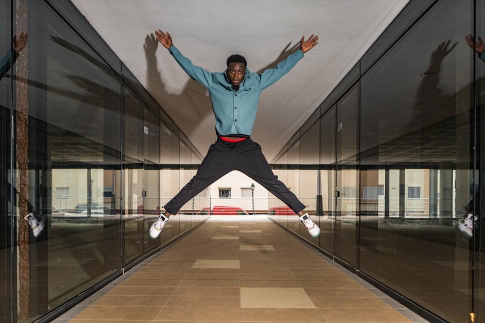 Free Image of Trendy serious black man jumping in passage and looking at camer 