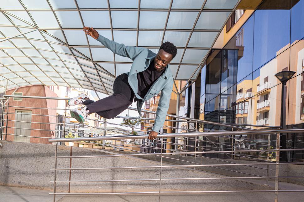Free Image of Happy black male millennial jumping over railing near modern bui 