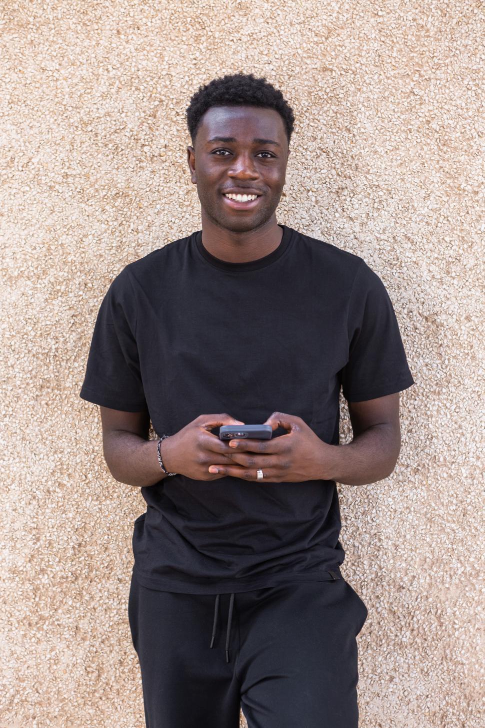 Free Image of Happy African American man messaging on smartphone 