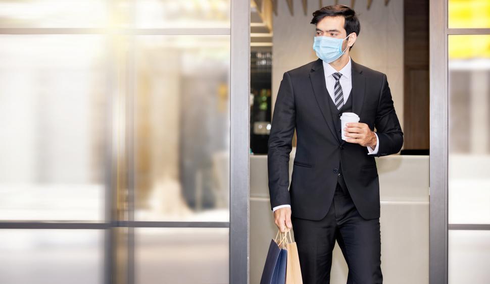Free Image of Man in a suit carries a shopping bag and coffee 