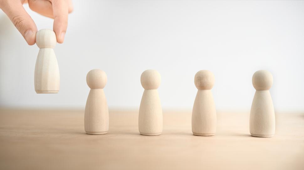 Free Image of Hand chooses the wooden dolls, Concept of satisfaction and choice 