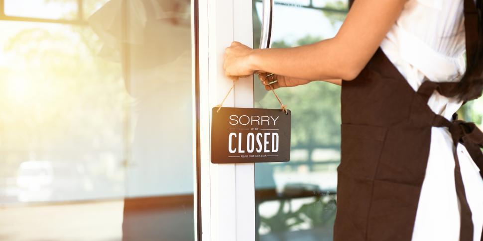 Free Image of The shopkeeper hanging a CLOSED sign on the door 