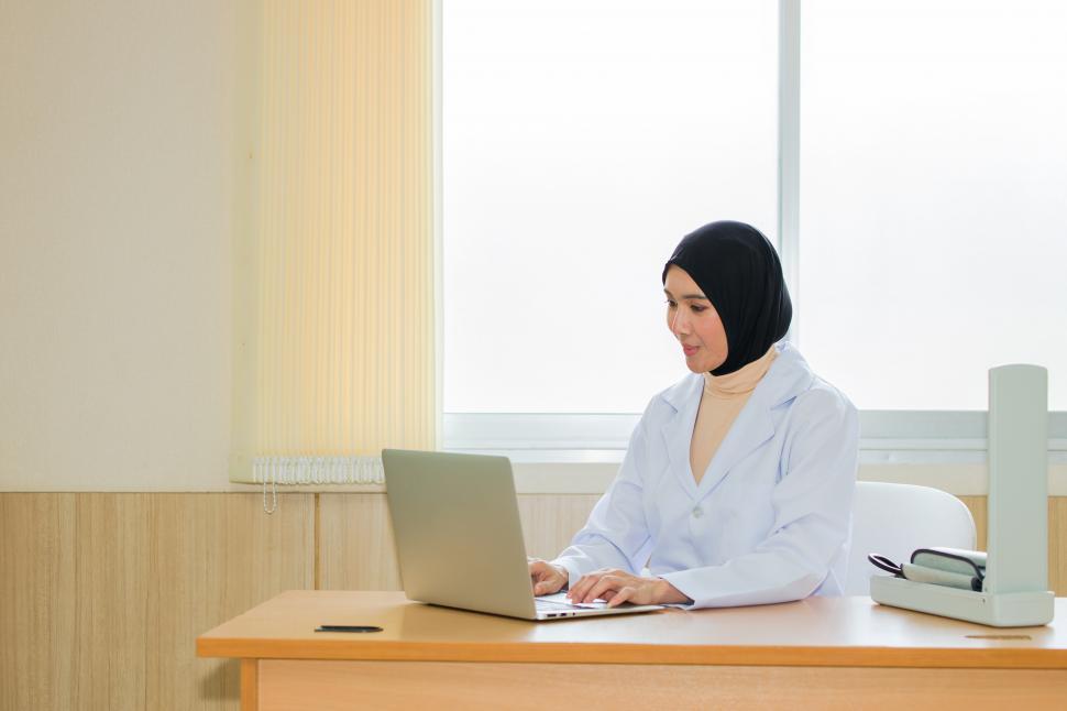 Free Image of Arab female doctor using laptop in examination room. 