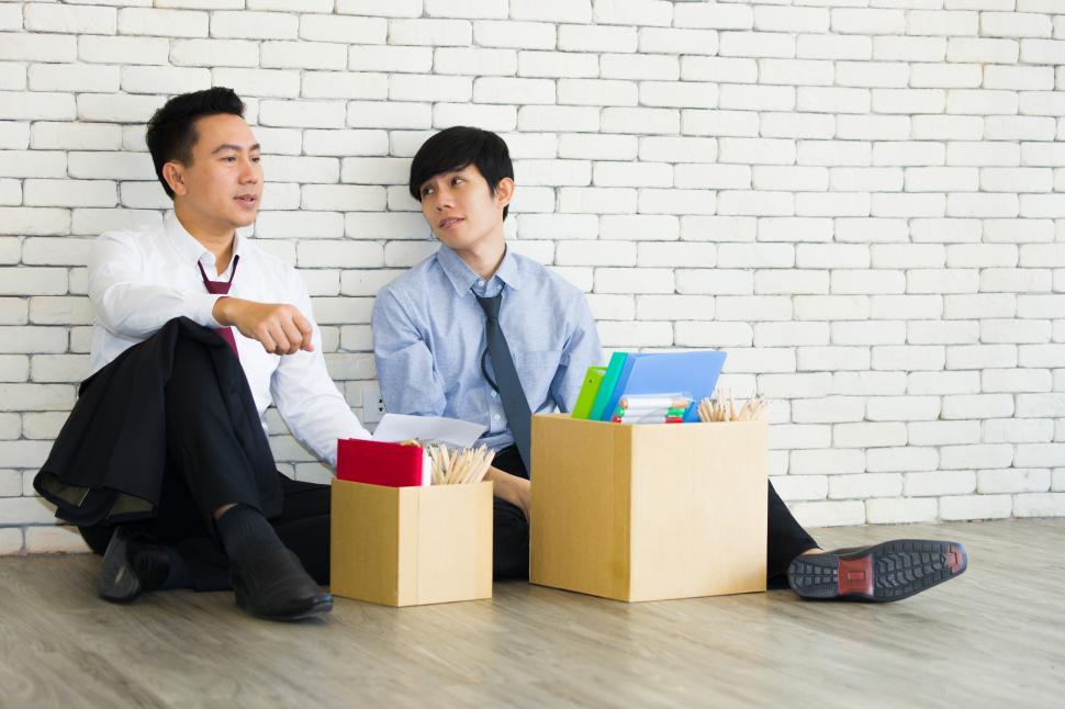Free Image of Two male workers fired from work sit together 
