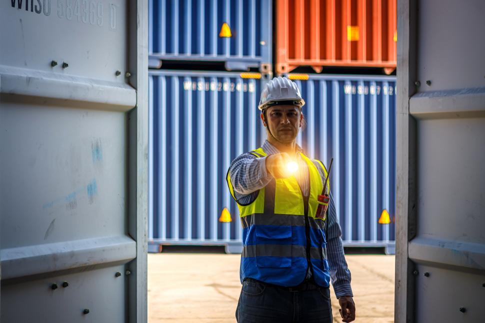Free Image of Engineer holding a flashlight opens a cargo container 