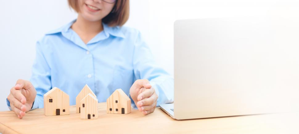 Free Image of Female hands showing protect a wooden model house. 