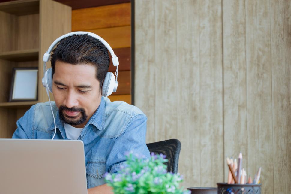 Free Image of Business Owner wearing earphones and using a laptop 