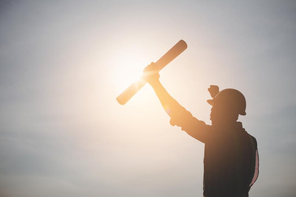 Free Image of Silhouette of engineer holding blueprints in hand. 
