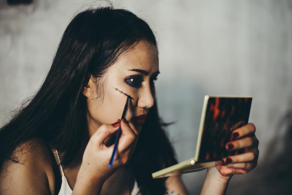 Free Image of Young woman applies halloween makeup. Face art design,. 