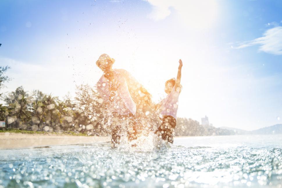 Free Image of Happy father splashing together with son on the beach 