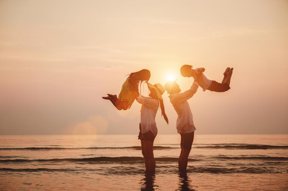 Free Image of Silhouette of the happy family playing in the surf at sunset 