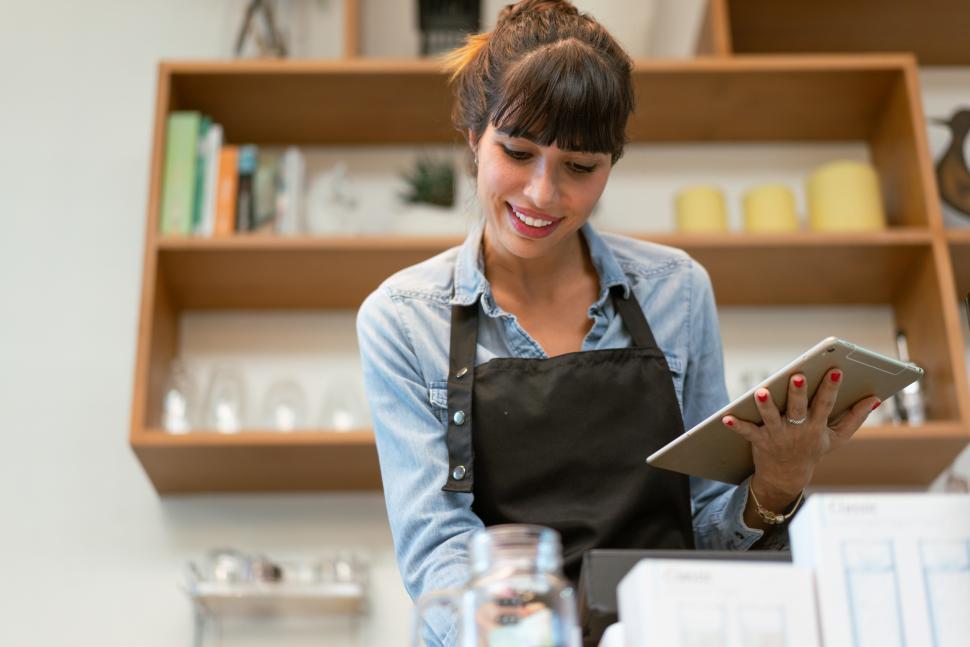 Free Image of Smiling female coffee shop owner using digital tablet receiving 