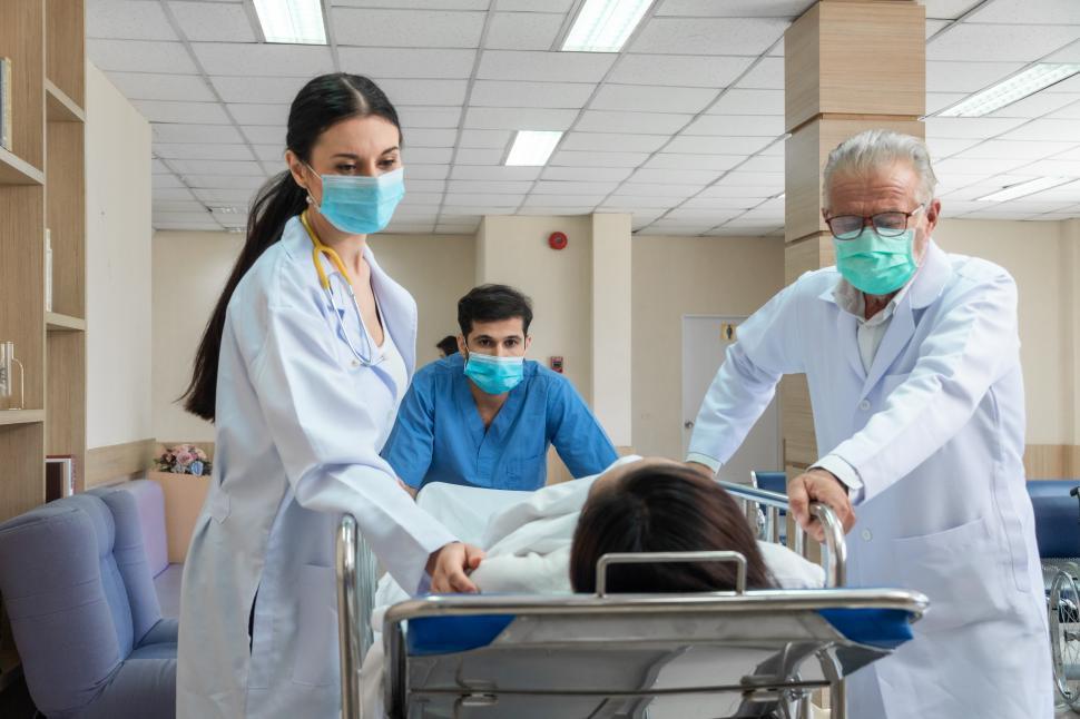 Free Image of Paramedics wheeling patient on gurney to treatment 
