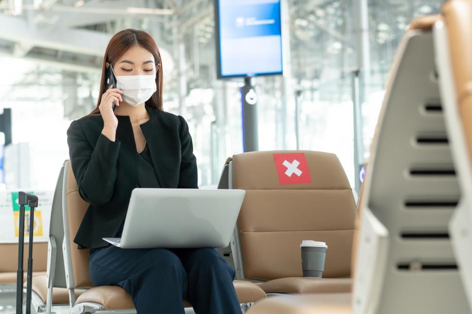 Free Image of Business woman wearing mask using laptop at airport 