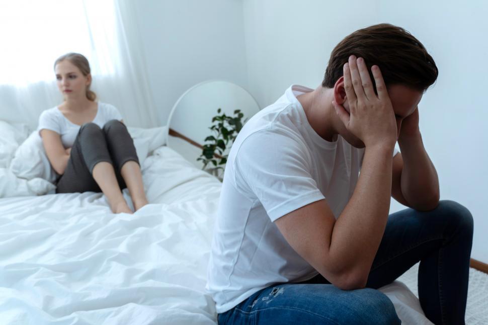 Free Image of Depressed husband sitting on the edge of the bed after the fight 