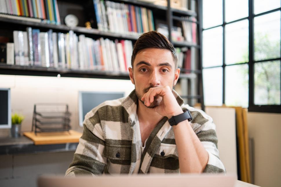 Free Image of Portrait of male employee in casual thinking and sitting at desk 