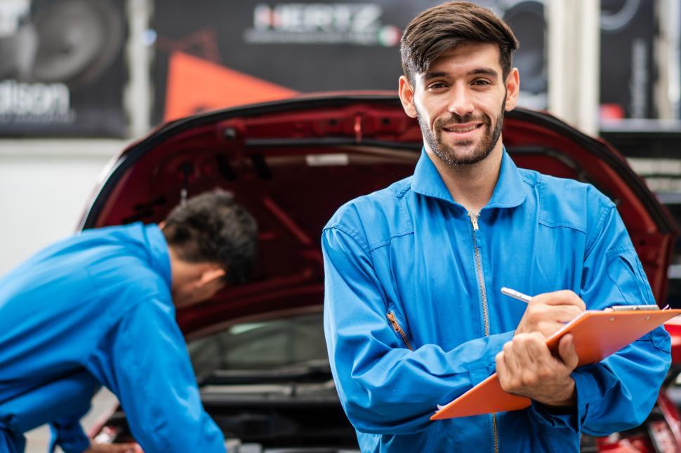 Free Image of Car mechanic man writing on maintenance document 