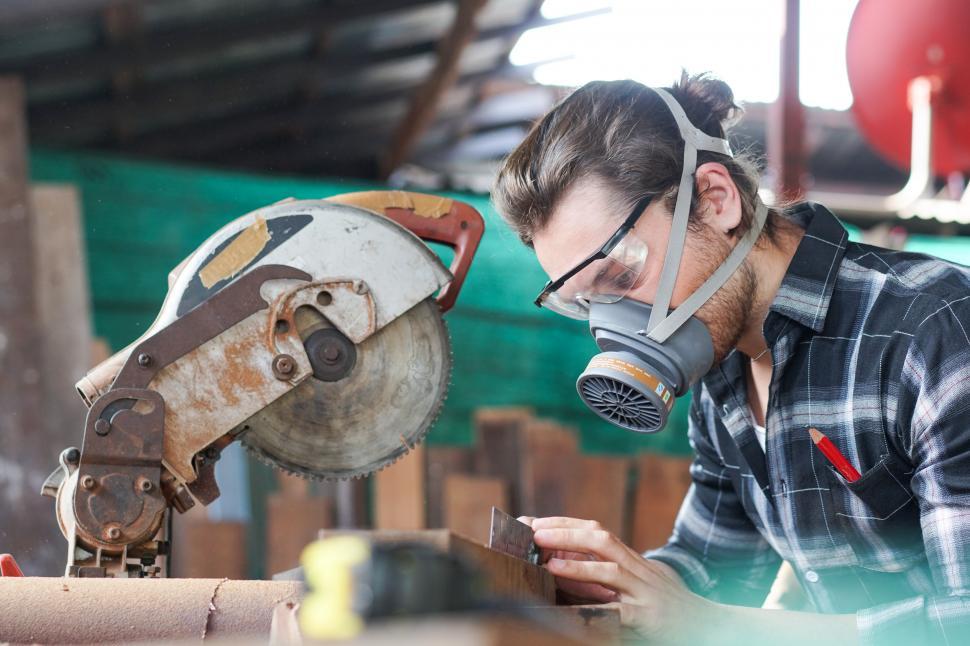 Free Image of Male carpenter wearing protective mask using electric circular chop saw 