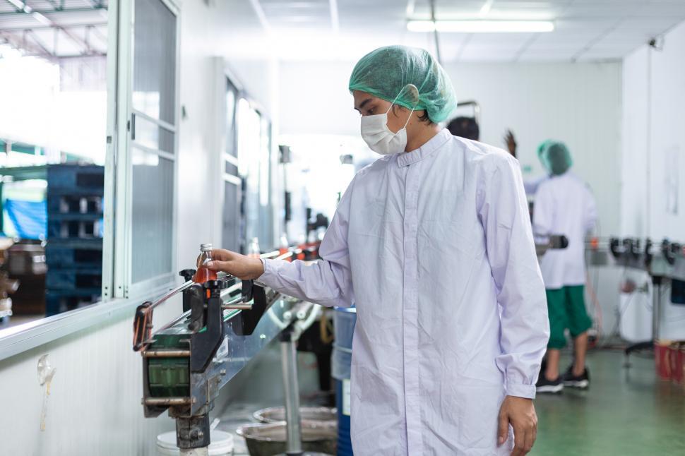 Free Image of Male factory putting bottle into production line machine 