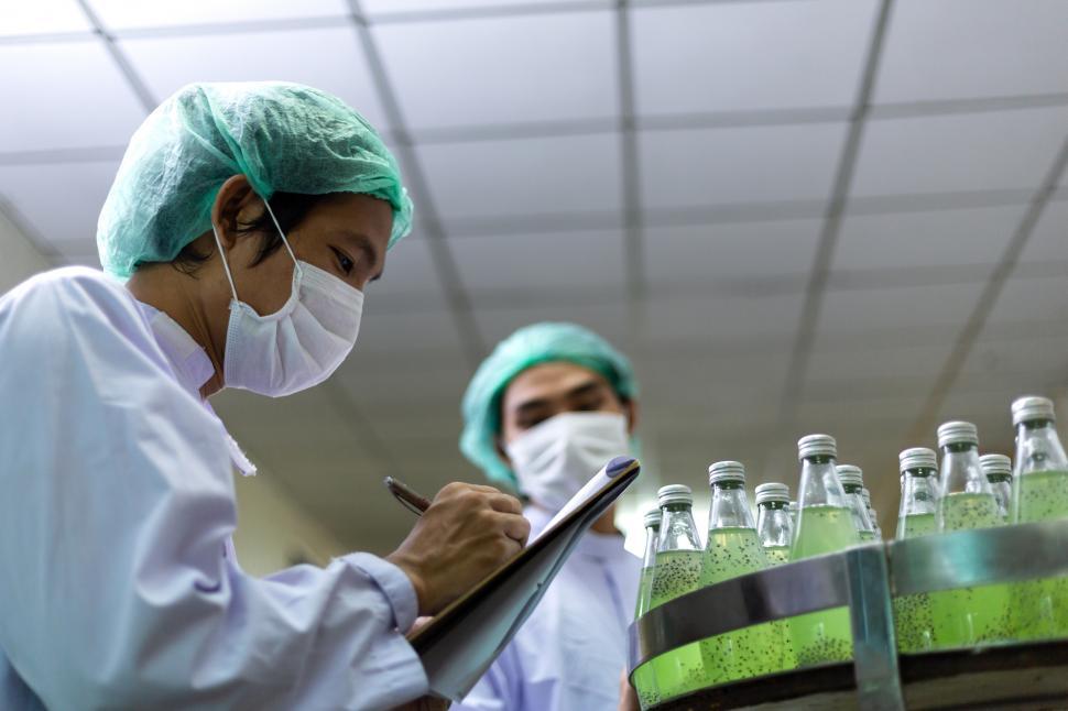 Free Image of Male worker checking drink bottle on bottling machine 
