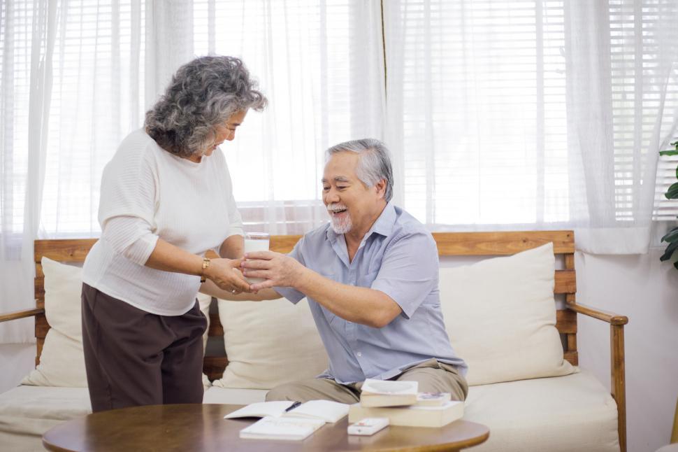 Free Image of Senior woman bringing glass of milk to older husband 