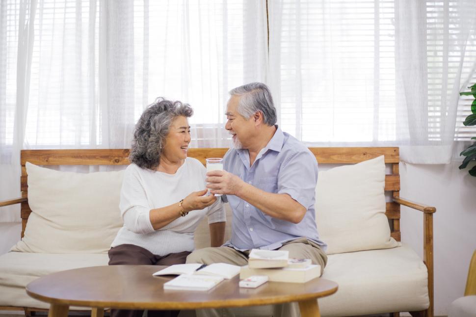 Free Image of Woman brings glass of milk to husband in living room 