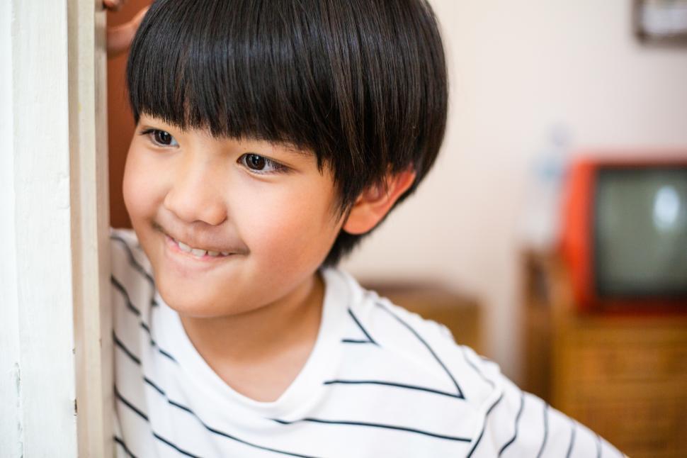 Free Image of Boy playing hide and seek or peeking around a corner at home 