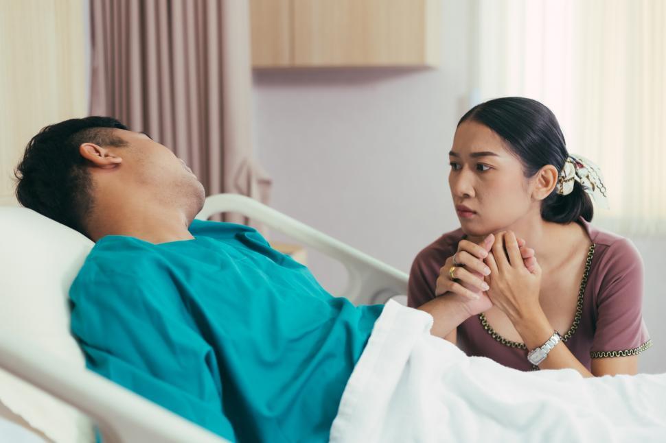 Free Image of Wife holding hand and look worried at husband on bed 