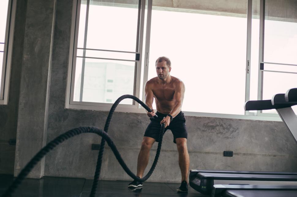 Free Image of Intense muscular man training with battle rope in the gym 