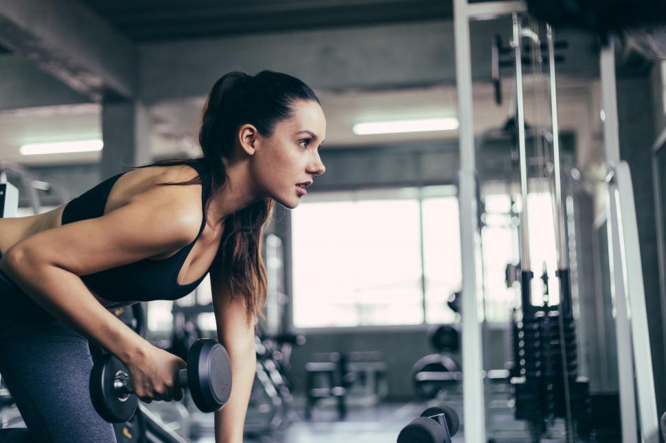 Free Image of Caucasian fitness woman lifting dumbbell at gym 