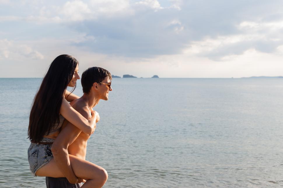 Free Image of Happy woman enjoying piggyback ride at the beach 