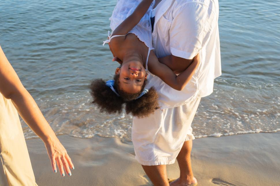 Free Image of Playful father carrying daughter at the beach 