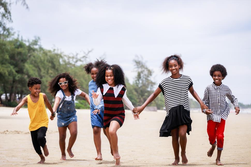 Free Image of Children run together holding hands at the beach 
