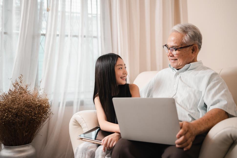 Free Image of Happy retired grandfather and pretty granddaughter watch laptop together 