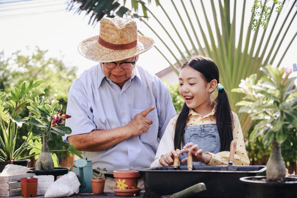 Free Image of Granddaughter helping grandfather plant in the garden 