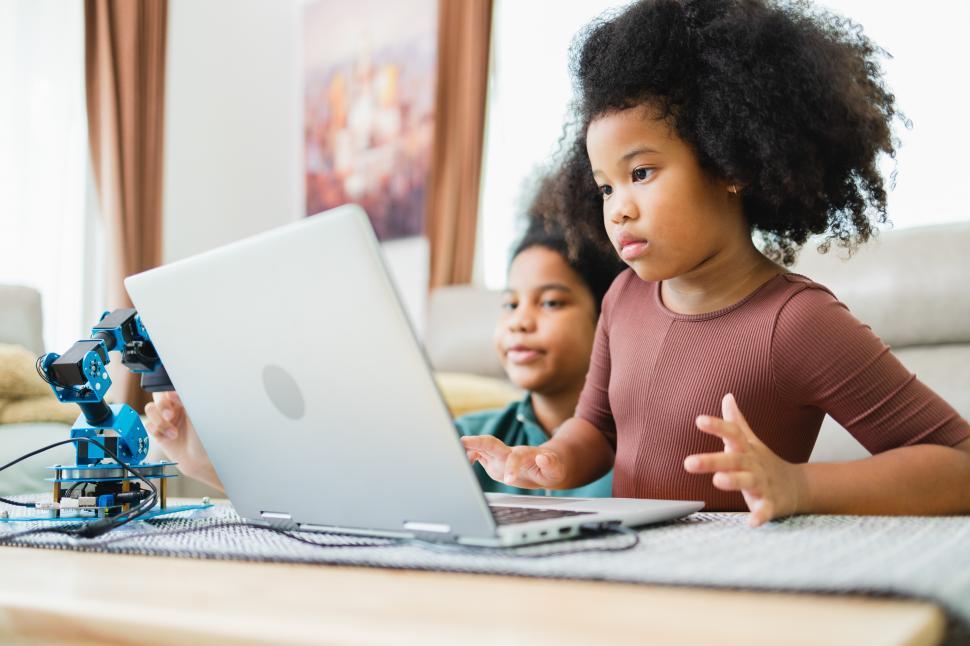 Free Image of Young girl programs robotic arm while big sister looks on 